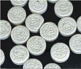 Photograph of several round, white pills with a stamped image of a Smurf.